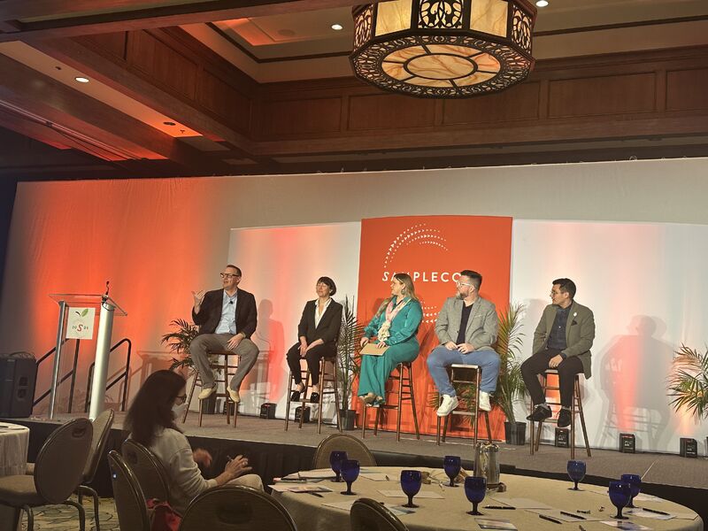 SampleCon panelists on stage, seen from the audience.