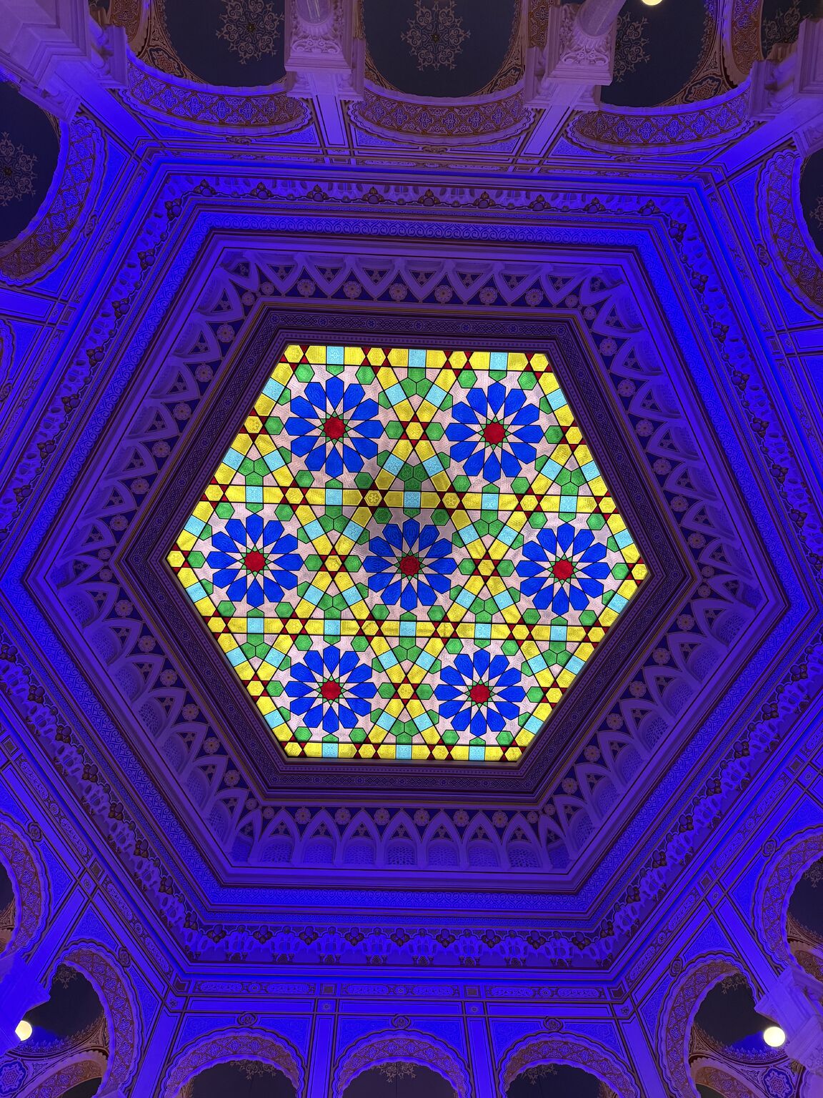 A colorful star-patterned stained-glass ceiling lit in blue.