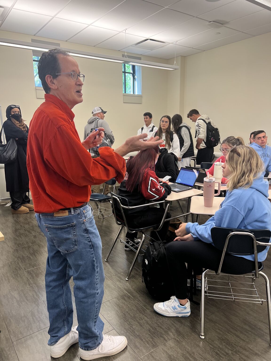 AJ Keirans, in a red shirt, speaking to a Seton Hall University market research class in a classroom.